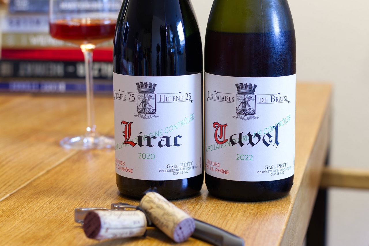 Zwei Flaschen Wein vom Weingut Seehaldenhof stehen auf einem Holztisch. Dahinter stehen ein Weinglas und ein Stapel Bücher.